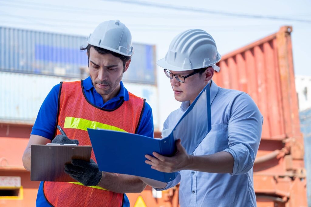 Foreman and cargo container worker discuss together with document in workplace area